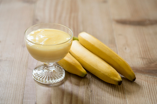 Banana Pudding Dessert In A Glass Cup On A Wooden Table.