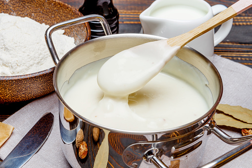 Preparation Of Bechamel Sauce In A Pan And Ingredients On The Wooden Table