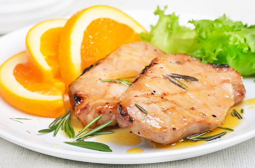 Pork Cutlets With Orange Sauce On White Plate, Close Up View